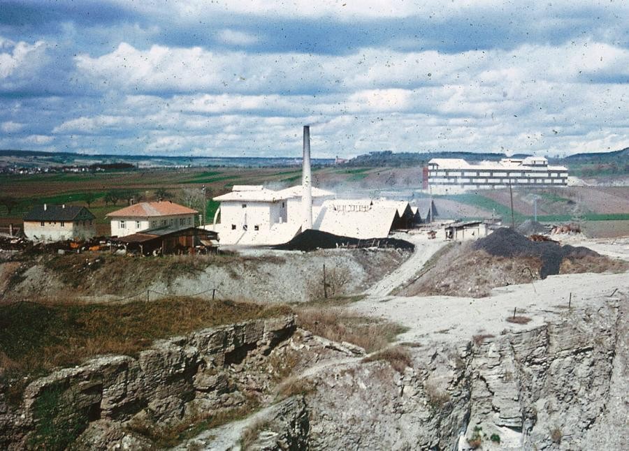 Gebäude mit Schornstein, Staub in der Luft, in einer Landschaft mit Tagebau